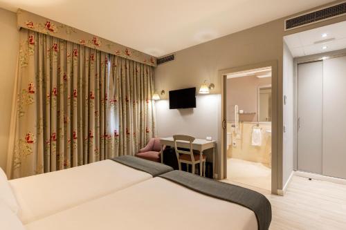 a hotel room with a bed and a desk and a room at Hotel PAX Torrelodones in Torrelodones