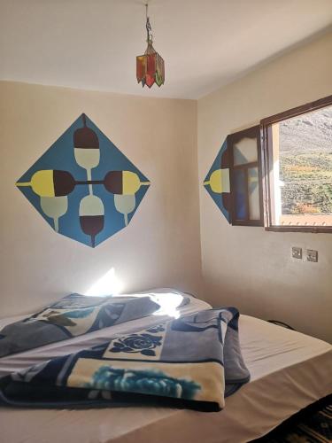 a bedroom with a bed with a painting on the wall at Gite Angour Tacheddirt in Tacheddirt