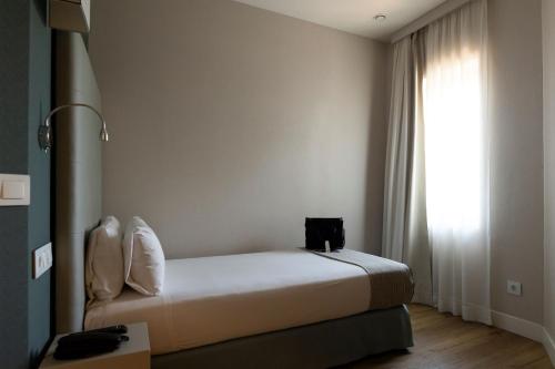 a bedroom with a bed and a large window at Hotel PAX Torrelodones in Torrelodones