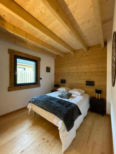 une chambre avec un grand lit dans une pièce en bois dans l'établissement Chalet cosy & confort haut de gamme - Sauna, Spa, Clim, à Anould