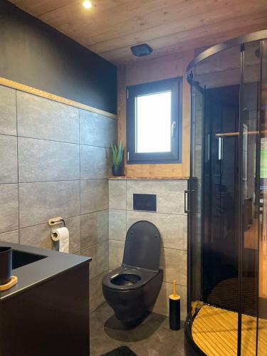 La salle de bains est pourvue de toilettes noires et d'une fenêtre. dans l'établissement Chalet cosy & confort haut de gamme - Sauna, Spa, Clim, à Anould