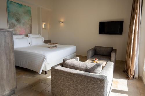 a bedroom with a bed and a couch and a chair at Coquillade Provence - Relais & Châteaux in Gargas