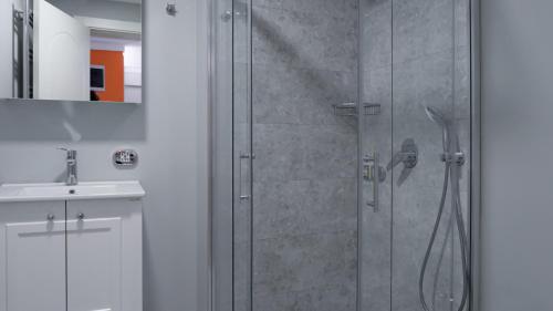 a shower with a glass door next to a sink at OTTO Tunalı Houses in Ankara
