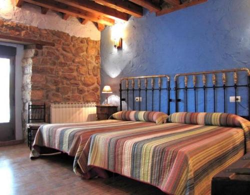 Un dormitorio con una cama grande en una pared de piedra. en Las Frascuelas, en Almajano