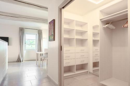 a walk in closet with white cabinets and a mirror at Coquillade Provence - Relais & Châteaux in Gargas
