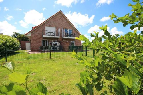 a brick house with a fence in the yard at Haus-am-See-Kolkstr-1-EG-rechts in Norddeich