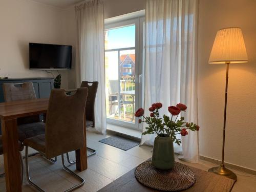 a living room with a table with a vase of flowers at Haus-am-See-Kolkstr-1-OG-rechts in Norddeich