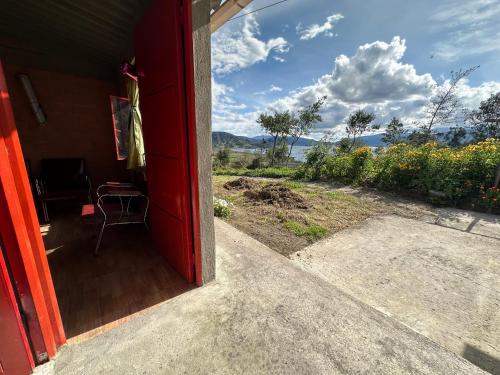 an open door of a red house with a view of a field at Vista al Lago, Cabaña Privada in Pasto