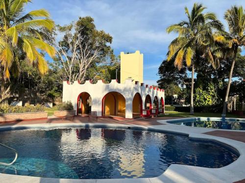 a swimming pool in front of a building with palm trees at Villita en la floresta in Ajijic