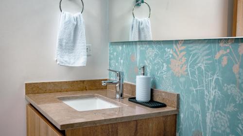 a bathroom with a sink and a towel on the wall at Ambar Roca Suites by Huespedia in Puerto de Gaira
