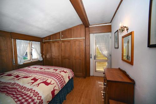a bedroom with a bed and a table and windows at Homeby, Casa Due Vette in Cortina dʼAmpezzo