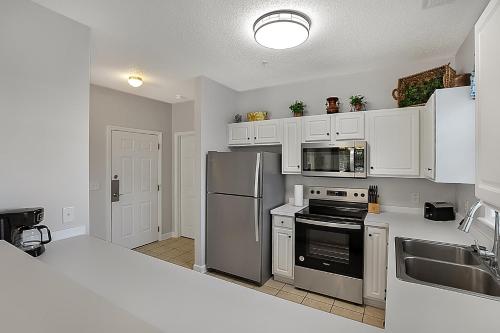 a kitchen with white cabinets and a stainless steel refrigerator at The Norman Retreat At Barefoot Resort! 3 Bedroom in Myrtle Beach