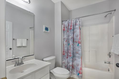 a white bathroom with a toilet and a shower at The Norman Retreat At Barefoot Resort! 3 Bedroom in Myrtle Beach