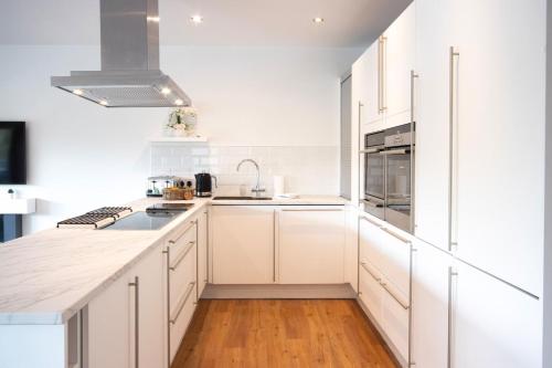 a white kitchen with white cabinets and wood floors at Waters Edge 04, Waterside Lodge P in South Cerney