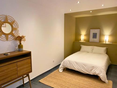 une chambre avec un lit, une commode et un miroir dans l'établissement Sous les Toits de Wambrechies, à Wambrechies