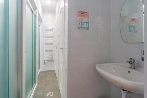 a white bathroom with a sink and a mirror at Grassalkovich Residence in Budapest
