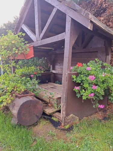 a wooden structure with flowers in the grass at Gîte al fontaine in La Roche-en-Ardenne