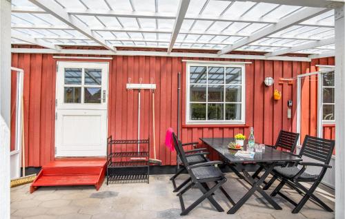 a patio with a table and chairs and a red wall at Two-Bedroom Holiday Home In Nexo in Neksø