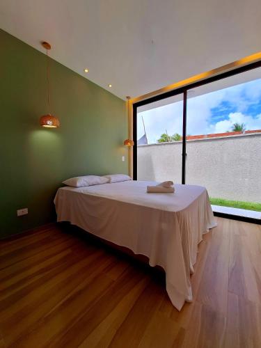 een slaapkamer met een bed en een groot raam bij Casa Sunset in Itacaré