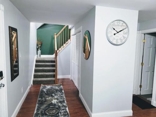 a hallway with a clock on the wall and stairs at Nice house with private parking, king bed fenced yard in West Seneca