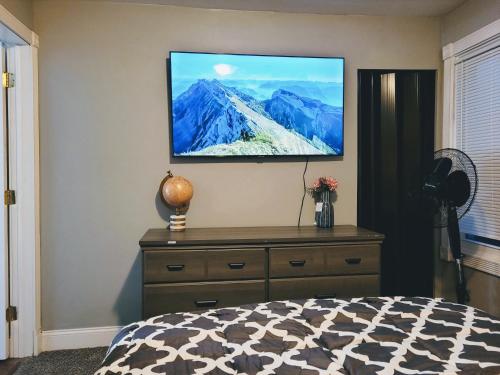 a bedroom with a flat screen tv on a wall at Nice house with private parking, king bed fenced yard in West Seneca