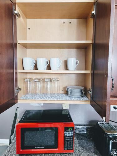a red microwave in a kitchen with cups and plates at Nice house with private parking, king bed fenced yard in West Seneca
