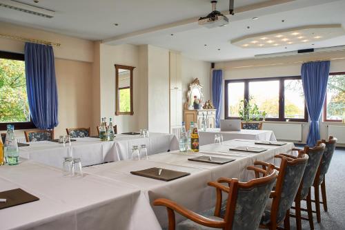 a dining room with white tables and chairs and windows at Hotel Restaurant Waldschlößchen in Lienen