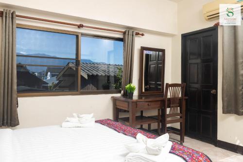 a bedroom with two beds and a desk and a window at Sripoom House 1 in Chiang Mai
