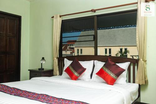 a bedroom with a bed with red and white pillows at Sripoom House 1 in Chiang Mai