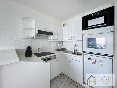une cuisine avec des appareils électroménagers blancs et des armoires blanches dans l'établissement Le Panoramique Marin- 2Ch, à Bray-Dunes