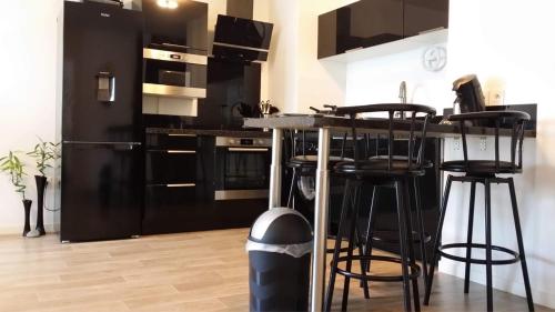 une cuisine avec des placards noirs et un bar avec des tabourets dans l'établissement Rivadour, à Bayonne