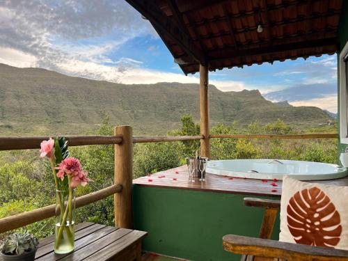 a deck with a bath tub and a table with flowers at Vila Verde in Palmeiras