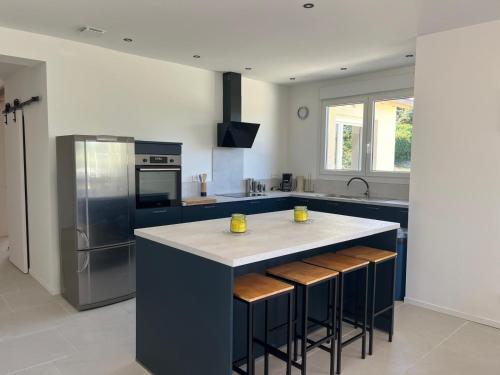 une cuisine avec un grand îlot et des tabourets de bar dans l'établissement Gîte Périgord 14 personnes avec piscine, à Rouffignac-Saint-Cernin-de-Reilhac