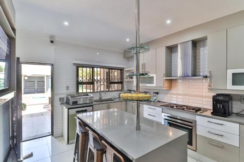 a kitchen with white cabinets and a island in it at Lefatshe La Rona Guesthouse in Springs
