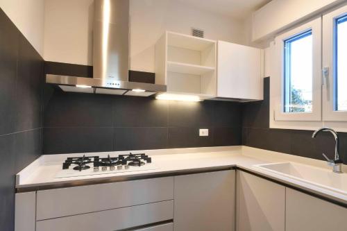 a kitchen with white cabinets and a stove top oven at CasaTitti Polcenigo in San Giovanni
