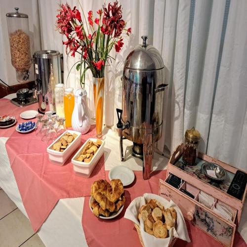 Bologna Hotel Mar del Plata في مار ديل بلاتا: طاولة عليها مفرش وردي اللون عليها طعام وزهور