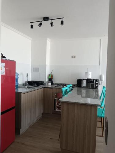 a kitchen with a red refrigerator and wooden cabinets at Departamento familiar Iquique in Iquique