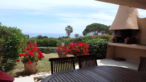 a table with two chairs and red flowers on a patio at Résidence les Hameaux de Bocca del Oro in Porto-Vecchio