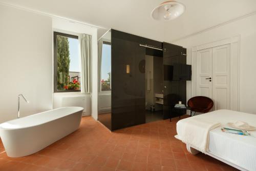 ein weißes Badezimmer mit Badewanne und Bett und einem Bett und Badewanne in der Unterkunft Mastropà Exclusive Resort in Massafra