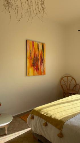 a painting hanging on a wall next to a bed at Villa OOM in Essaouira