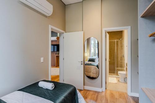 een slaapkamer met een bed en een badkamer met een spiegel bij Luxo e Estilo no centro by Achei Gramado in Gramado