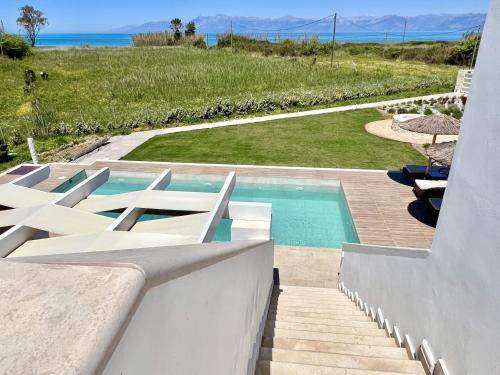 a pool with white lounge chairs and the ocean at Danune Luxury Beachfront Villa with private pool by DadoVillas in Astrakeri