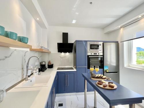 a kitchen with blue cabinets and a table with glasses of wine at Danune Luxury Beachfront Villa with private pool by DadoVillas in Astrakeri