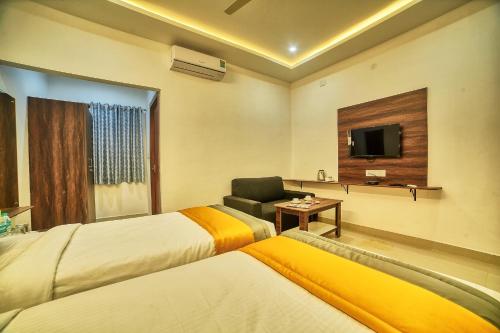 a hotel room with two beds and a chair and a television at Hotel Visa Inn 4kms from Airport l Free Airport pickup & drop 24x7 in Bengaluru