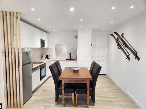 une cuisine avec une table en bois et des chaises noires dans l'établissement appartement T3 avec jardin proche village, à Saint-Bonnet-en-Champsaur