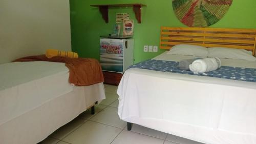 a bedroom with two beds and a refrigerator at Pousada Recanto Sapoti in Barreirinhas