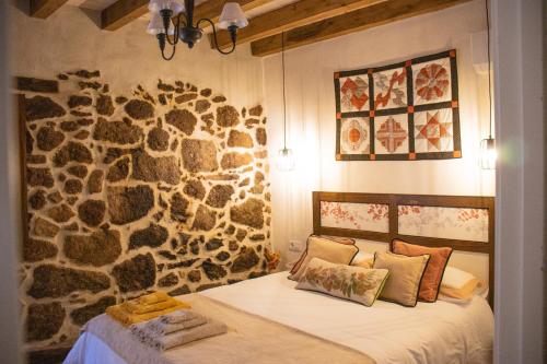 Un dormitorio con una pared de piedra con una cama. en La Casita de los Pájaros, en San Martín de Valdeiglesias