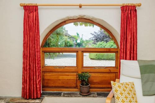 an arched window with red curtains in a living room at The Coach House 5 star property in Inistioge