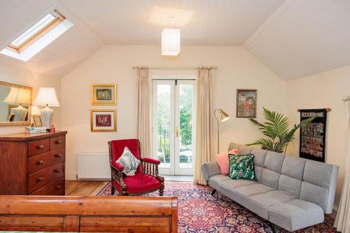 a living room with a couch and a red chair at The Coach House 5 star property in Inistioge