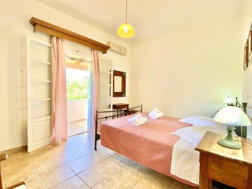 a bedroom with a bed and a table and a window at Kostas Beach Estate with private pool by DadoVillas in Astrakeri